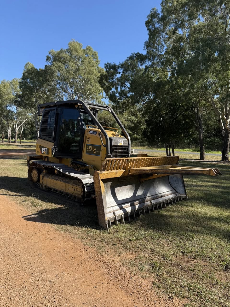 CAT D3K2 dozer with LEH branding parked on a dirt track, blade clean, gum trees behind