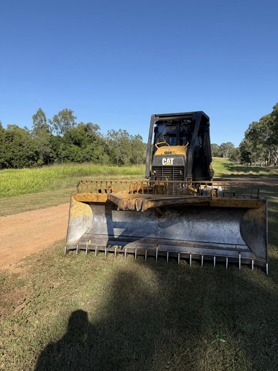 CAT D3K2 dozer photographed head-on with blade lowered, eucalypt clearing behind